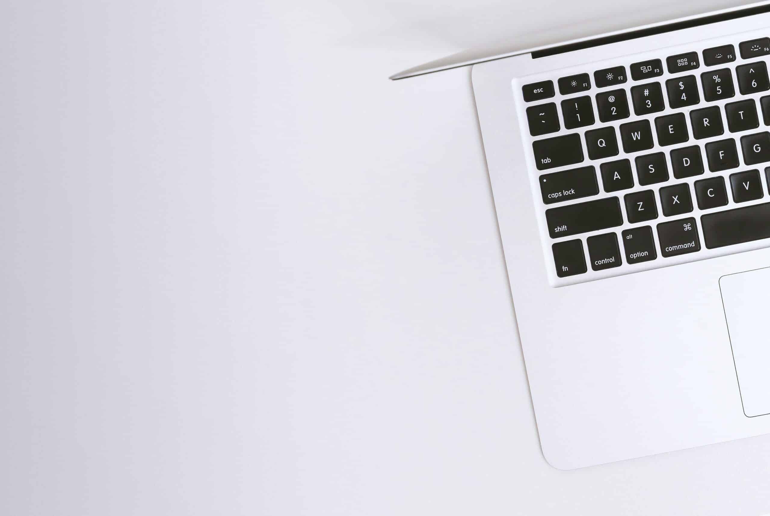 Free Aerial view of a sleek laptop keyboard on a clean, white surface, ideal for tech backgrounds. Stock Photo